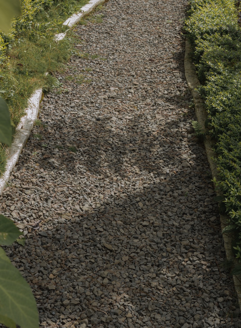 White house by a stream with a view of a forested hill.